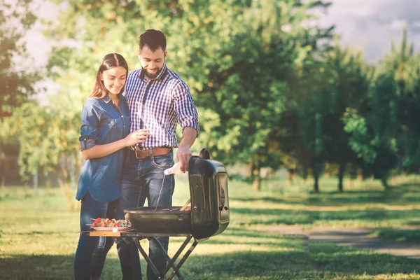 Друзья готовят барбекю и обедают на природе. Пара весело провести время во время еды и питья на пикник - Счастливые люди на барбекю . — стоковое фото