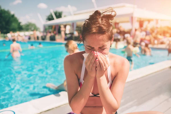 picture from a Beautiful women in bikini with handkerchief. Sick female model has runny nose. girl makes a cure for the common cold. She is sick in the summer on vacation.