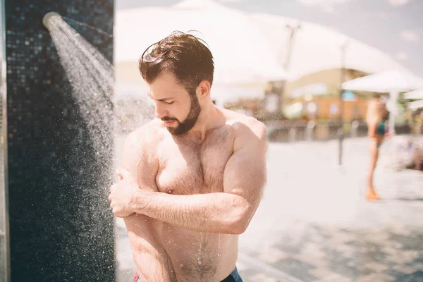 Stilig man tar en dusch på stranden. — Stockfoto