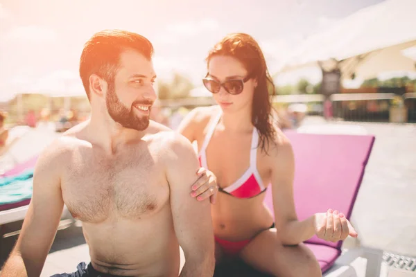 Pareja aplicando crema solar. Feliz joven mujer aplicando crema en novios espalda . — Foto de Stock