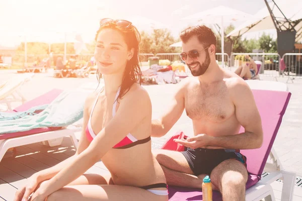 Pareja aplicando crema solar. Feliz joven aplicando crema a las novias espalda — Foto de Stock