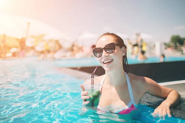 Chica morena con cócteles relajante en la piscina. Mujer sexy en bikini disfrutando del sol de verano y bronceado durante las vacaciones en la piscina con bebida . — Foto de Stock
