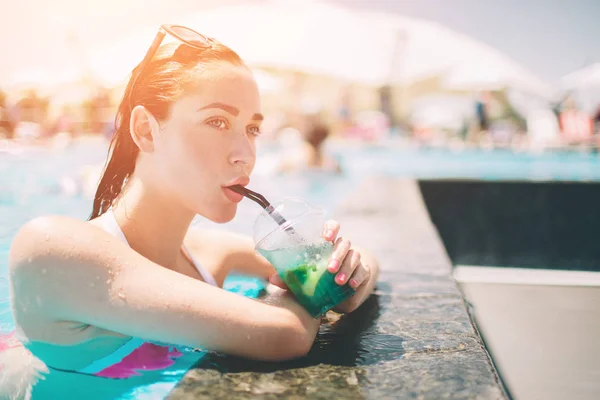 Chica morena con cócteles relajante en la piscina. Mujer sexy en bikini disfrutando del sol de verano y bronceado durante las vacaciones en la piscina con bebida . —  Fotos de Stock