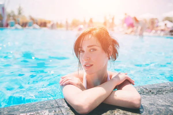 Portrait of beautiful tanned woman in white swimwear relaxing in swimming pool spa. Hot summer day and bright sunny light. — Stock Photo, Image