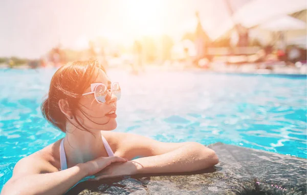 Retrato de una hermosa mujer bronceada en traje de baño blanco relajante en el spa de la piscina. Día de verano caliente y luz soleada brillante . —  Fotos de Stock