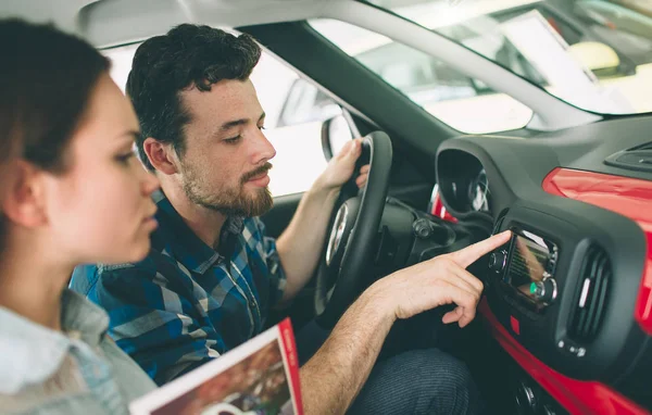 Bella giovane coppia in piedi presso la concessionaria scegliendo l'auto da acquistare — Foto Stock