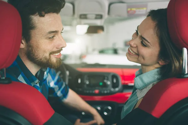 Bella giovane coppia in piedi presso la concessionaria scegliendo l'auto da acquistare — Foto Stock