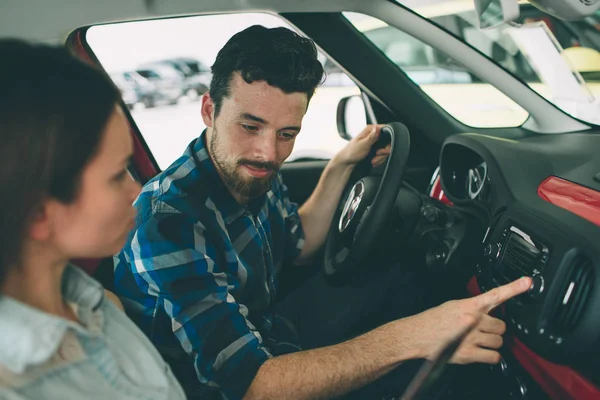 Beau jeune couple debout à la concession en choisissant la voiture à acheter — Photo