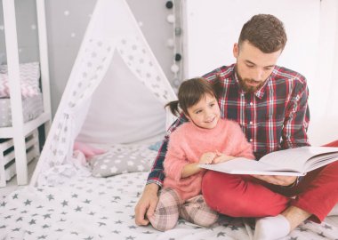 Baba yatak odasında yerde yatarken kızına bir kitap okuyor. Şirin küçük kızı ve yakışıklı genç babası çocuk odasında birlikte oynuyorlar..