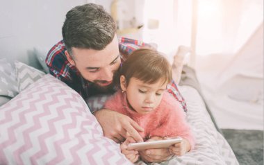 Şirin küçük kızı ve yakışıklı genç babası çocuk odasında birlikte oynuyorlar. Baba ve çocuk, yatak odasında yerde otururken birlikte vakit geçiriyorlar.