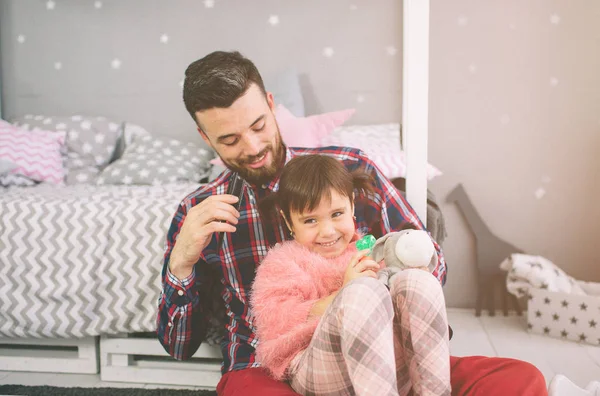 Söt liten dotter och hennes stiliga unga pappa leker tillsammans i barnrummet. Pappa och barn tillbringar tid tillsammans sittande på golvet i sovrummet. — Stockfoto