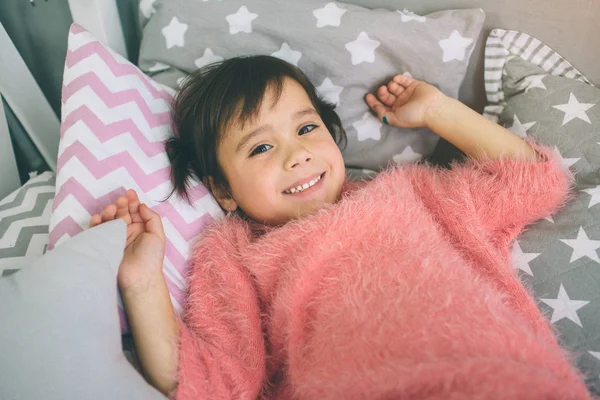 Közelkép az aranyos kis lány rózsaszín ruhát az ágyon. Többi otthon — Stock Fotó