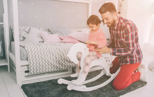 Mignonne petite fille et son beau jeune père jouent ensemble dans la chambre des enfants. Papa et enfant passent du temps ensemble tout en étant assis sur le sol dans la chambre . — Photo