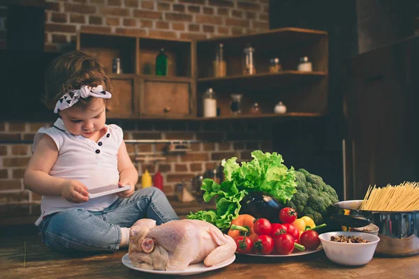 Pe masa din bucătărie folosind un smartphone. Copil și tehnologie . — Fotografie, imagine de stoc