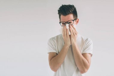 Studio resim mendil ile genç bir adamdan. Hasta adam izole burun akıntısı var. soğuk algınlığı ilacı kılıyor. İnek gözlük takıyor.
