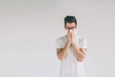 Studio resim mendil ile genç bir adamdan. Hasta adam izole burun akıntısı var. soğuk algınlığı ilacı kılıyor. İnek gözlük takıyor.