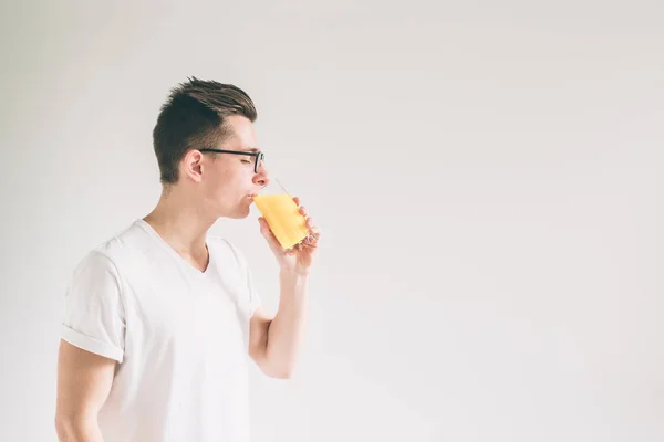 Glücklicher Mann mit einem Glas Orangensaft auf weißem Hintergrund. Nerd trägt Brille — Stockfoto
