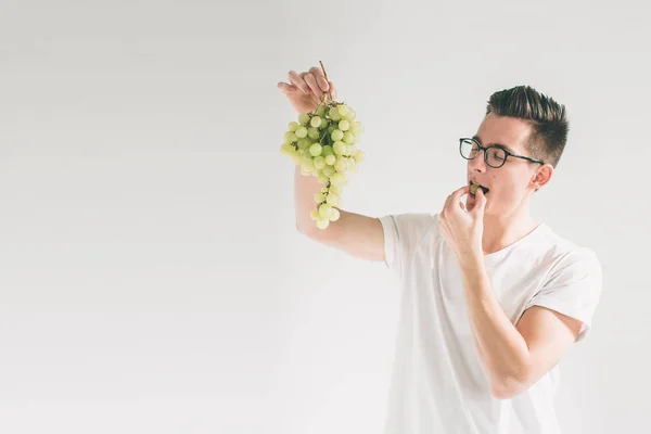 Homem segurando uva, de perto. conceito. isolado em branco. Nerd está usando óculos — Fotografia de Stock