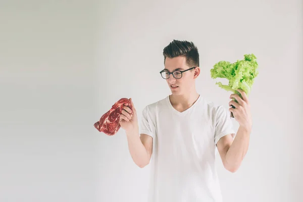 Vegetarisches Konzept. Mann bietet eine Auswahl an Fleisch oder Gemüse Salatblätter. Nerd trägt Brille. — Stockfoto