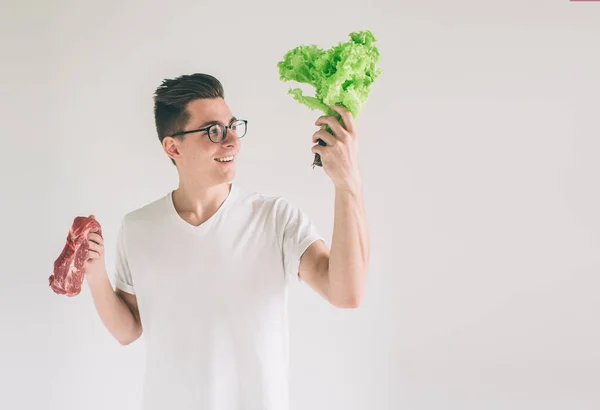 Vegetarisches Konzept. Mann bietet eine Auswahl an Fleisch oder Gemüse Salatblätter. Nerd trägt Brille — Stockfoto