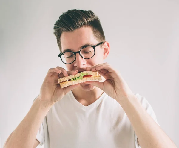 Mann mit einem Stück Hamburger. Student isst Fast Food. kein hilfreiches Essen. sehr hungriger Mann. Nerd trägt Brille. — Stockfoto