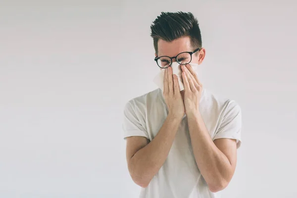 Atelierbild eines jungen Mannes mit Taschentuch. Kranker Mann isoliert hat laufende Nase. Mann macht Heilmittel gegen Erkältung: Nerd trägt Brille. — Stockfoto