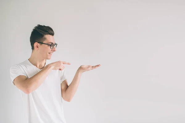 Nerd trägt eine Brille, die etwas Fantastisches in der einen Hand hält, d.h. Mann auf weißem Hintergrund. — Stockfoto