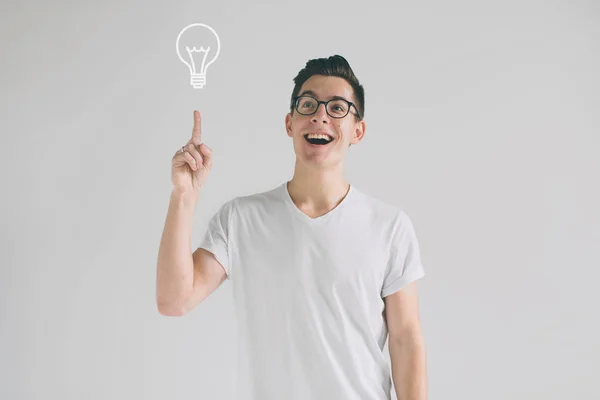 Χαμογελαστός νεαρός έχοντας μια καλή ιδέα. Πορτρέτο του μια ενθουσιασμένος σπασίκλα με γυαλιά και ένα λευκό T-shirt τεντωμένο επάνω στο copyspace απομονωθεί σε λευκό φόντο. — Φωτογραφία Αρχείου