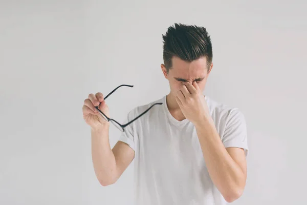 Close up portrait of an attractive man with eyeglasses. Poor young guy has eyesight problems. He is rubbing his nose and eyes because of weariness. Close up portrait of a funny man with eyeglasses — Stock Photo, Image