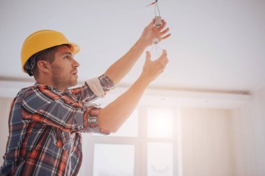 Yakışıklı genç üreticisi bir sarı inşaat kask içinde ampul içinde büküm. Adam arıyor .