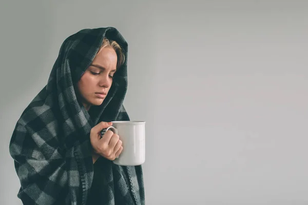 Studio obrázek z mladé ženy s kapesníkem. Nemocná dívka, samostatný má rýmu. Ženský model pije horký čaj a snaží se zahřát. Ona drží pohár v rukou — Stock fotografie