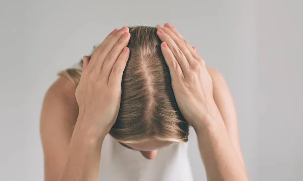 Cabelo das mulheres é uma vista superior close-up. Mulher loira está vestindo camisa isolada no branco . — Fotografia de Stock