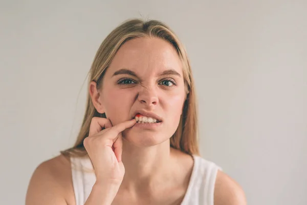 Uma foto horizontal de uma jovem mulher preocupada em camisa quadriculada sofrendo de forte dor de dente e tocando sua bochecha — Fotografia de Stock