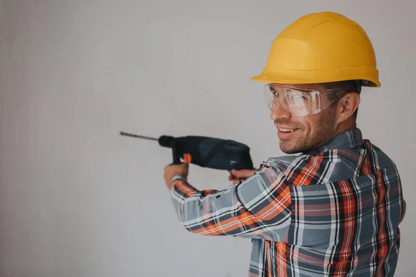 Працівник будівельника з обладнанням, що робить отвір у стіні на будівельному майданчику — стокове фото