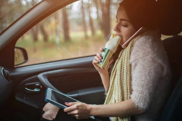 Mujer ocupada está en un apuro, ella no tiene tiempo, ella va a comer bocadillos en el camino. Trabajador comiendo y hablando por teléfono al mismo tiempo. Ella multitarea mientras come y trabaja en una tableta PC — Foto de Stock