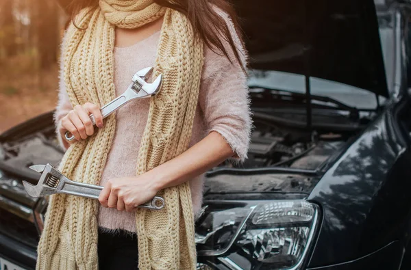 Mylić, młoda kobieta, patrząc na podziale silnik samochodu na ulicy posiada klucz — Zdjęcie stockowe