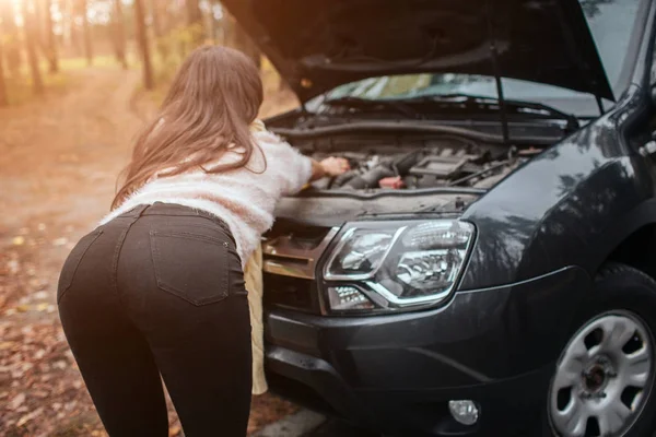 Mujer joven confundido mirando averiado coche motor reparación de coches en la calle — Foto de Stock