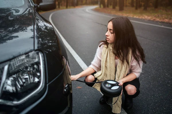Mylić, młoda kobieta, patrząc na uszkodzony dół silnika samochód naprawy na ulicy — Zdjęcie stockowe