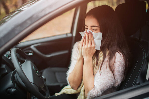 young woman with handkerchief. Sick girl has runny nose. female model makes a cure for the common cold in the car
