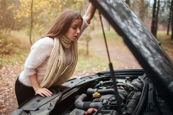 壊れた見て混乱している若い女性、路上修理車のエンジンを — ストック写真