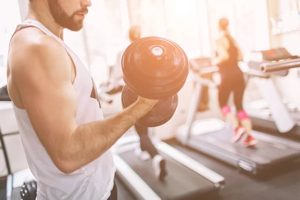 Homem barbudo muscular durante o treino no ginásio. atleta musculoso fisiculturista no ginásio de treinamento bíceps com halteres. Aptidão interior — Fotografia de Stock