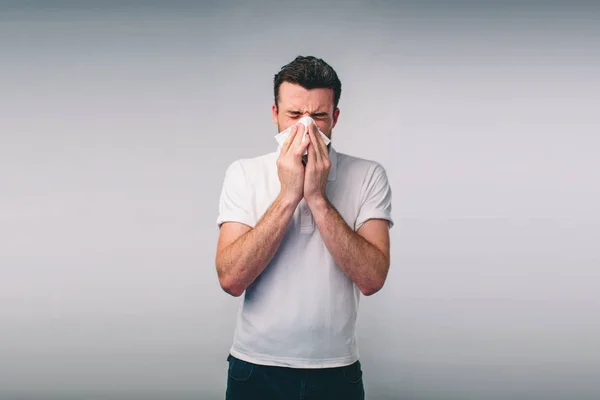 Imagen de estudio de un joven con pañuelo. El enfermo aislado tiene secreción nasal. hombre hace una cura para el resfriado común.Nerd está usando gafas —  Fotos de Stock