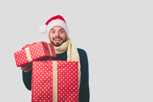 Handsome man in a Christmas hat holding gifts on white background — Stock Photo, Image