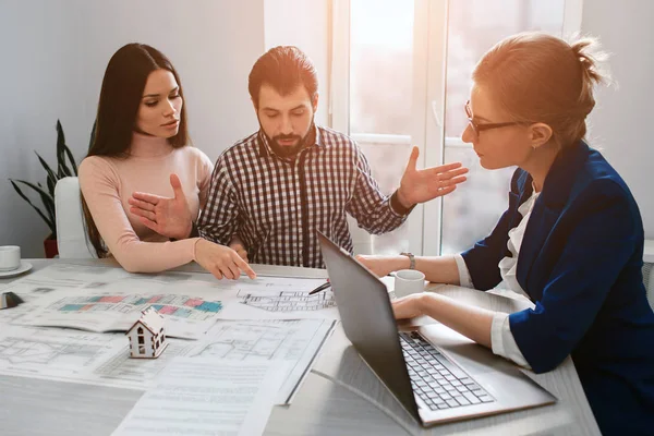 Familia joven pareja compra propiedades de alquiler de bienes raíces. Agente dando consulta a hombres y mujeres. Firma del contrato para la compra de casa o piso o apartamentos. Debate sobre el tamaño . — Foto de Stock