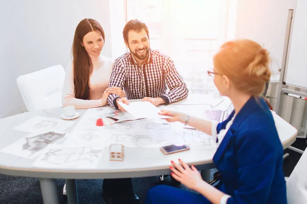 Agente de confianza con vendedores de casas detrás. Familia joven pareja compra propiedades de alquiler de bienes raíces. Agente dando consulta a hombres y mujeres. Firma del contrato para la compra de casa o piso o apartamentos —  Fotos de Stock