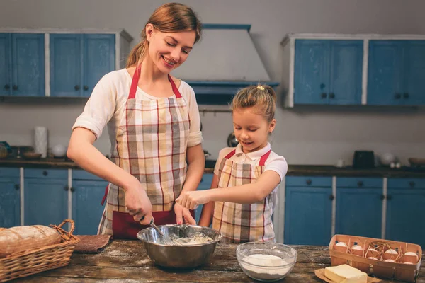 Cozinhar bolos caseiros. Feliz família amorosa estão preparando padaria juntos. Mãe e filha menina estão cozinhando biscoitos e se divertindo na cozinha. Rolar a massa . — Fotografia de Stock