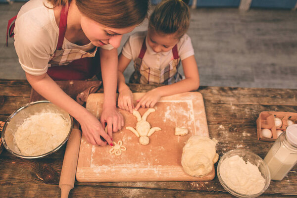 Готовить домашние торты. Счастливая любящая семья готовит пекарню вместе. Мать и дочь дочь девочка готовят печенье и веселятся на кухне. Бросай тесто.
.