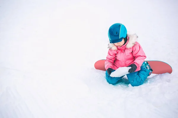 雪板冬季运动。小女孩穿着温暖的冬衣与雪玩耍。冬季背景 — 图库照片