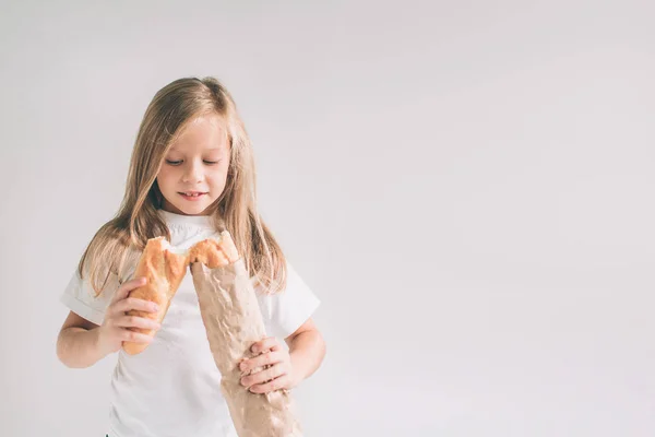 Chica con pan en la mano. Pan recién horneado en las manos. .. Niño está sosteniendo una gran cantidad de pan en las manos aisladas sobre fondo blanco . — Foto de Stock
