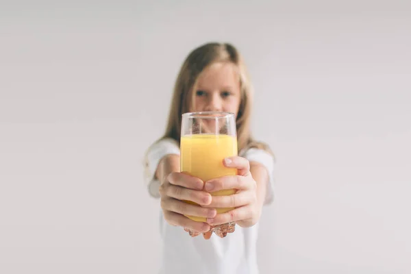 Happy girl holding glass of orange juice isolated on white background. Nerd is wearing glasses — Stock Photo, Image